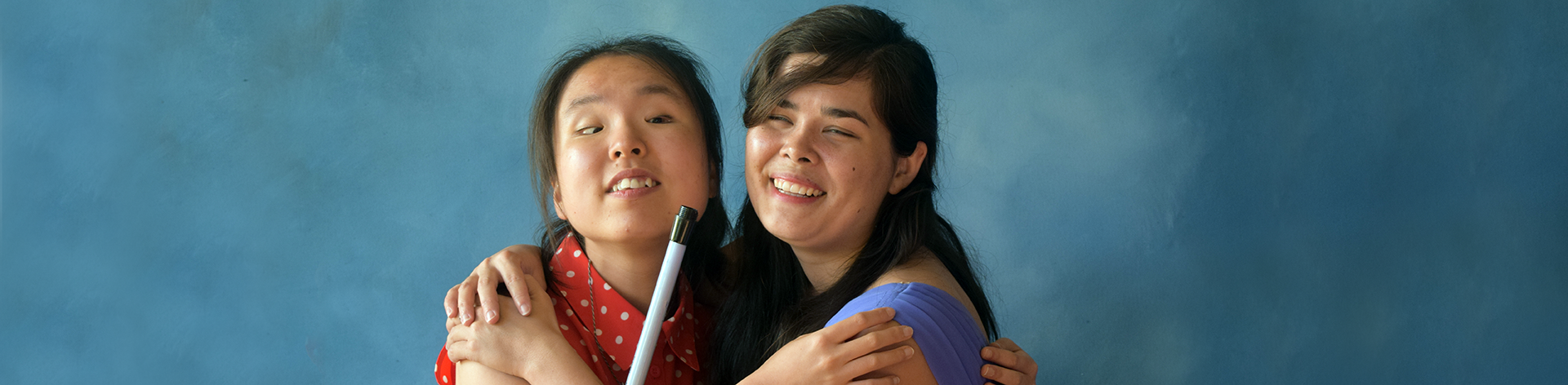 Two blind girls hug each other and smile.